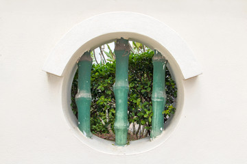 round hole - window in white wall of public garden at Buddhist monastery, Penang, Malaysia