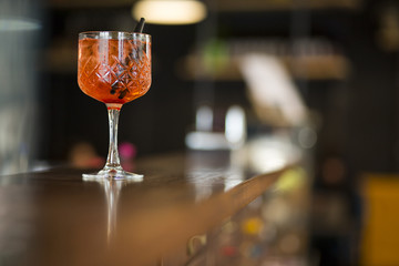 Dettaglio di un bicchiere con aperitivo colorato sopra il bancone di un bar