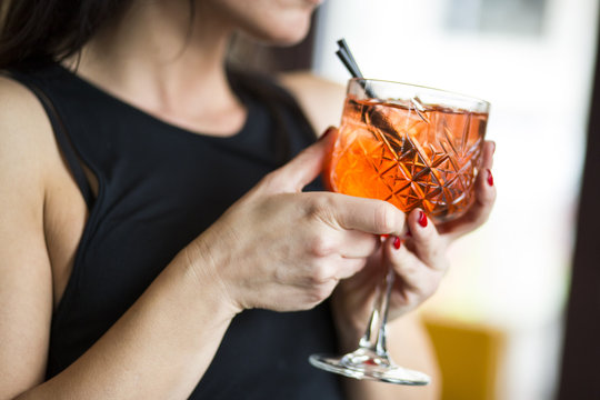 Dettaglio di un bicchiere con aperitivo colorato tenuto da una ragazza in un locale