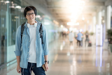 Young Asian happy man dressed in casual style standing with backpack in the international airport terminal, travel lifestyle concepts