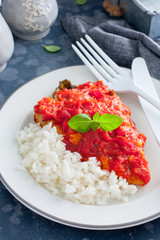 Flounder with tomato sauce and boiled rice, selective focus