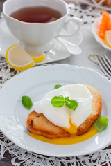 Bright breakfast with a cup of tea, white bread toast with poached egg and marmalade, selective focus