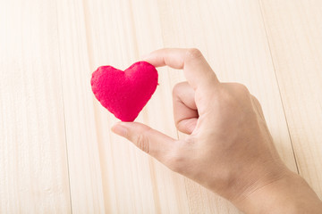 Fototapeta premium Red single heart with hand on wooden background