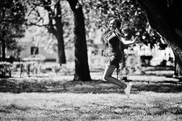 Cute and slim african american girl in red dress with dreadlocks jump outdoor in spring park. Stylish black model.