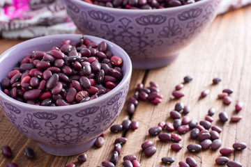 Red dry beans in a ceramic bowl on a wooden table, horizontal, copy space