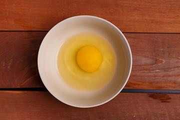 broken egg in ceramic bowl, ready to cook scrambled breakfast or omelette