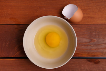 broken egg in ceramic bowl, ready to cook scrambled breakfast or omelette