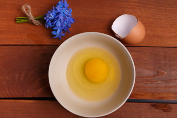 broken egg in ceramic bowl, ready to cook scrambled breakfast or omelette