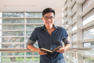 Young handsome cute men student smiles and reads a book in university