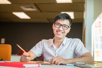 Young handsome cute Asian men student smiles and do homeworks in university