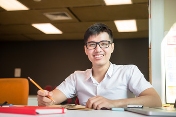 Young handsome cute Asian men student smiles and do homeworks in university