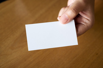 Obraz premium Closeup image of hands holding and giving an empty business card to someone on table in office