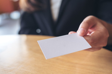 Business woman holding and giving  an empty business card to someone on table in office