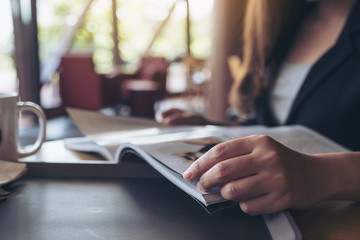 Closeup image of a business woman reading a book with coffee cup on table in cafe