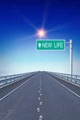 Straight highway with footprints and text New Life on the road sign. Concept of movement to changes