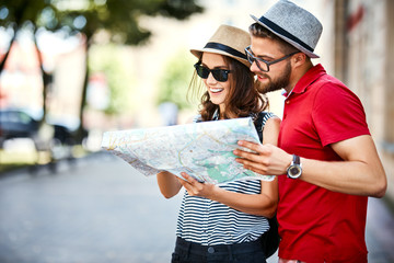 Young couple looking at map while on vacation during summer together