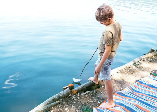 Boy launch paper boat in lake water