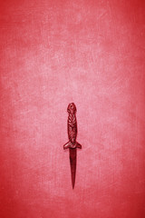 Small red Wiccan and witchcraft dagger on a textured red background with space for copy and text
