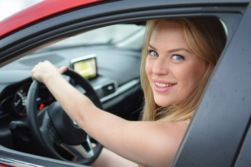 Fototapeta na wymiar Young, pretty blonde girl driving red car