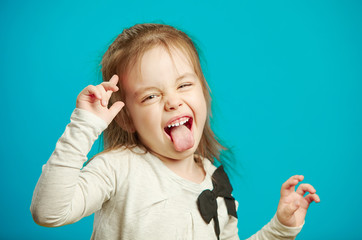 Angry little girl shows her tongue in funny grimace © Ilshat