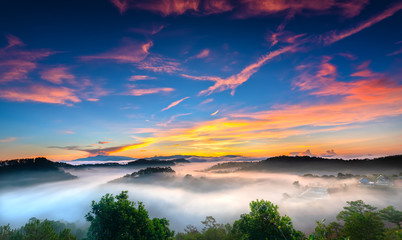 Sunrise over hillside as the sun rising from horizon reflect light bright yellow sky. Below cloudy mist covered valleys flooded pine forests create impressive beauty highlands in morning.