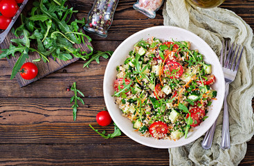 Salads with quinoa,  arugula, radish, tomatoes and cucumber in bowl on  wooden background.  Healthy food, diet, detox and vegetarian concept. Top view. Flat lay