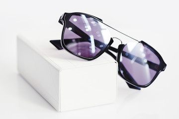 Fashionable sunglasses with box on white background