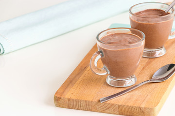 Dietary vegan dessert chocolate yogurt pudding serving cups wooden cutting boarding. Copy space.