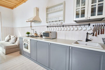 Wide angle shot of modern open living room with grey kitchen counters and white furniture in...