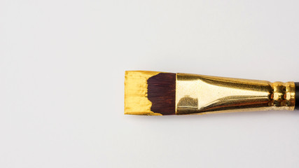 Paintbrush and gold colored poster on a white background.