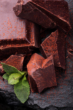 Dark chocolate stack, and powder.Closeup.With leaf of mint hocolate.Sweet delicious.On dark background