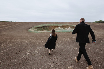 A dramatic love story of a guy and a girl who go separately through the field, say goodbye to each other with a look. Cloudy sky and a symbolic crater in the field as a place of farewell to love