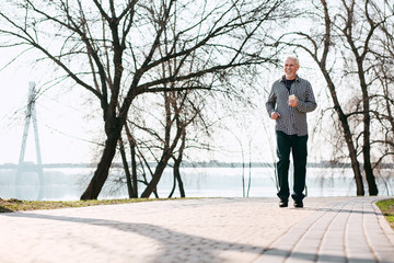 Nice weather. Optimistic senior man running and enjoying nature