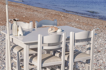 Four white chair and umbrella with wooden table on beach