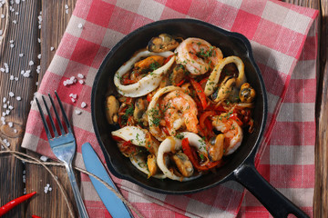 seafood in a frying pan top view on textile with cutlery