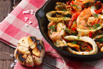 seafood in a frying pan close up with fried garlic