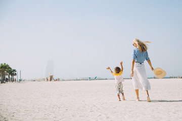 Young mother and happy little son at sandy beach in Dubai, UAE