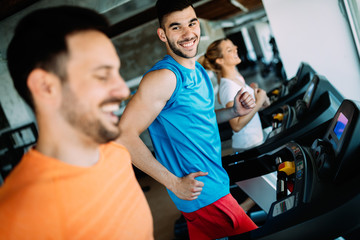 Fototapeta na wymiar Happy people on treadmills in the gym
