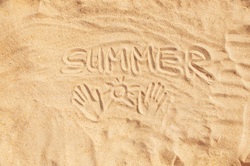 Inscription word summer and hand prints on sand.