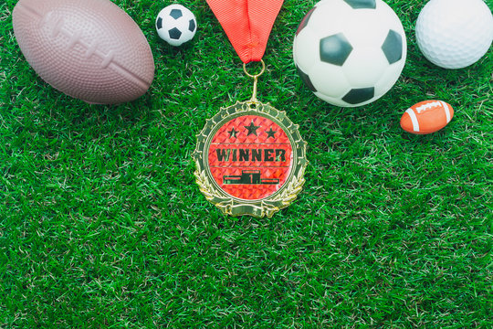 Table top view aerial image soccer or football tournament season background.Flat lay objects gold medal & ball on the artificial green grass wallpaper.Copy space for creative design mock up text.