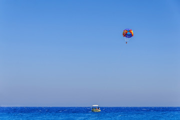 Fototapeta na wymiar Parachute skiing on blue wave sea and big clean sky
