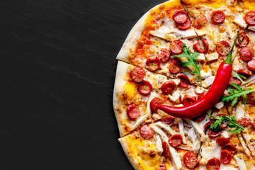 Pizza à la viande avec saucisse, fromage mozzarella et tomate sur fond de pierre noire avec espace de copie. Livraison de pizzas.