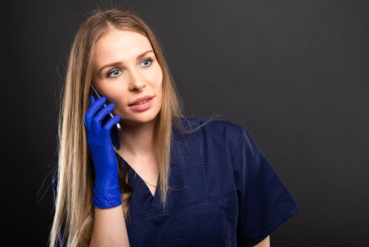 Female doctor wearing scrubs talking at smartphone.