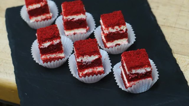 Closeup view of many small red cakes on a black plate served on a table in restaurants, cafes, top view.
