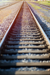 Fototapeta premium Straight Railroad track against sunshine. Shallow depth of field.