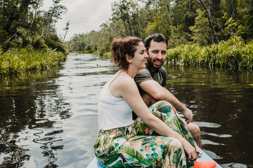 .Young tourist couple sailing on a wooden boat for a beautiful river in the borneo jungle, in Kalimantan. Excursion to see the island's wildlife. Travel Photography.