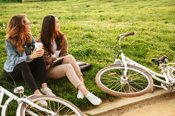 Two young beautiful women friends outdoors with bicycles