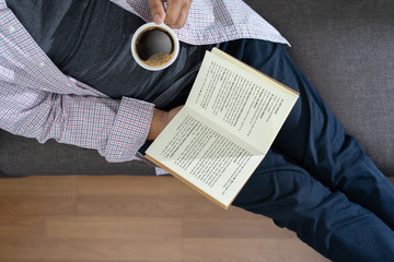 man reading a book and holding cup of coffee Sit Read Knowledge