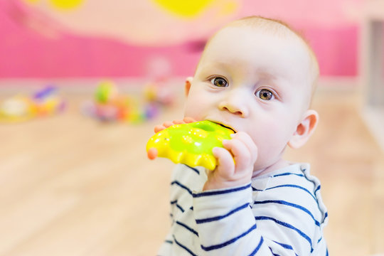 A Kid With A Toy In His Mouth.