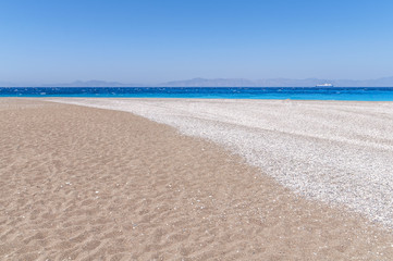 Fototapeta na wymiar Pebble beach and sea on summer day in the Rhodes beach
